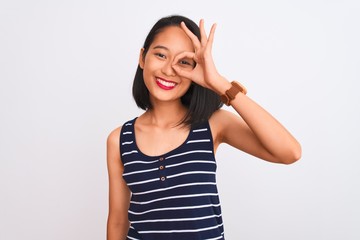 Obraz na płótnie Canvas Young chinese woman wearing striped t-shirt standing over isolated white background doing ok gesture with hand smiling, eye looking through fingers with happy face.
