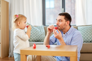 family, fatherhood and childhood concept - happy father and little daughter with toy crockery playing tea party at home
