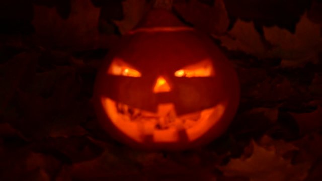 Panning forward on scary orange pumpkin with light inside 