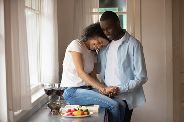 Obraz na płótnie Canvas Happy millennial mixed race woman embracing smiling african american husband.
