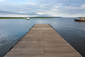 Wooden pier on sunny summer day with boats and forest in the background on Rio Tapajos, Para state, Brazil. Concept of leisure, vacation, travel, tourism and mindfulness.