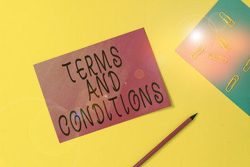 Writing note showing Terms And Conditions. Business concept for rules that apply to fulfilling a particular contract Blank paper sheets message pencil clips binder plain colored background