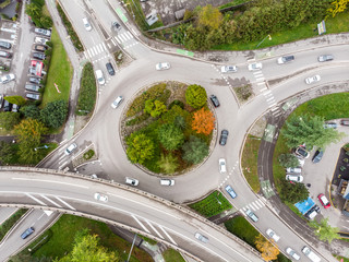 Roundabout road intersection with vehicle traffic and green trees aerial view from drone showing...