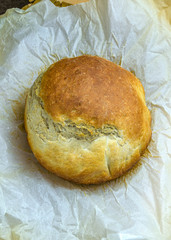 A sheet of baking paper with a newly baked home made crusty bread loaf. 