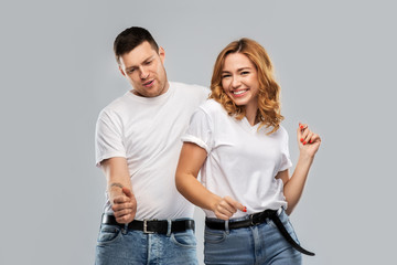 relationships and people concept - portrait of happy couple in white t-shirts dancing over grey background