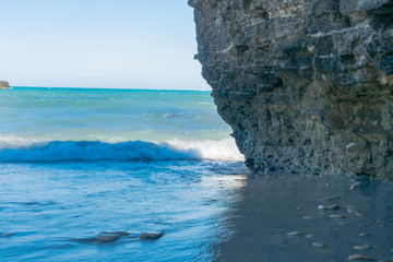 in a tiny bay waves come to the beach with the white foam