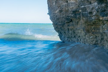water reach the tiny shady beach during a windy day of summer