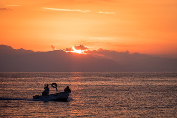 Fishing boat sailing in the sunset over the Mediterranean Sea in Cefalu, Sicily