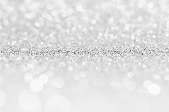 Silver white abstract light grey background, shining lights, sparkling glittering Christmas lights. Blurred abstract holiday background.