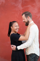 Interracial couple embraced by red wall