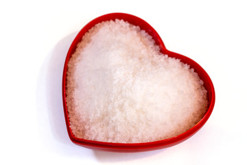 Salt inside a heart shaped container on a white background