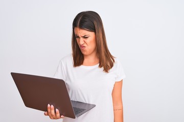 Beautiful young woman working using computer laptop over white background skeptic and nervous, frowning upset because of problem. Negative person.