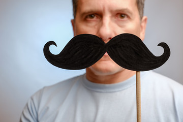 fake mustache on a stick in a man hand to participate in an event in November to help men awareness...