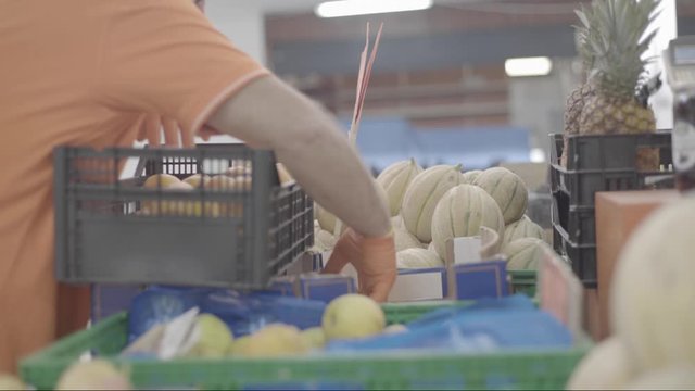 Commesso con frutta e verdura al mercato 