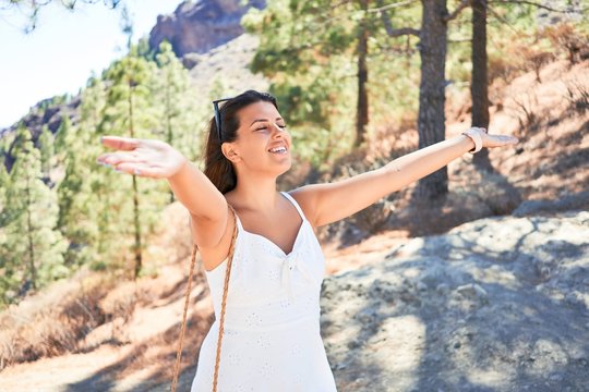 Young beautiful woman enjoying summer vacation on mountain landscape, traveler girl sunbathing with open arms