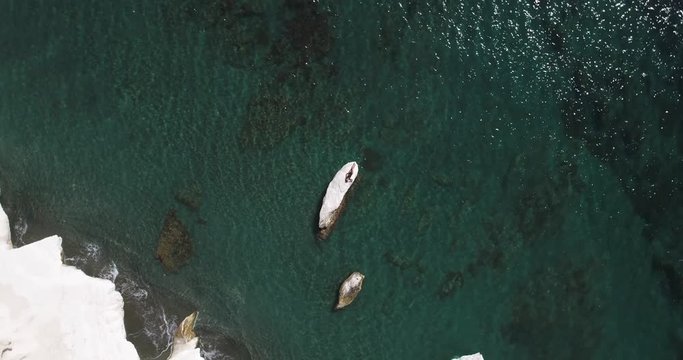 Aerial view of the Mediterranean coast line and beautiful girl with slim tanned body lying on the white rocks. Happy vacation and relaxing. Dron flying under beautiful girl. Cyprus, governor beach.