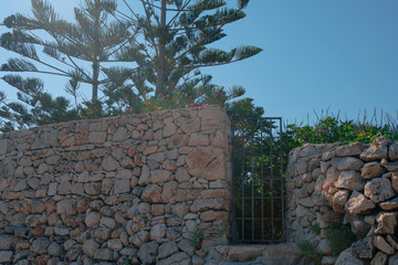 a picturesque stone wall and iron gate during a summer day
