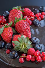 Partial view. Homemade Chocolate Cake. Chocolate bavaroise with chocolate topping. Garnished with red currants, strawberries. Dark background.