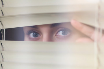 girl looks at you through the blinds