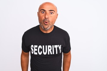 Middle age safeguard man wearing security uniform standing over isolated white background afraid...