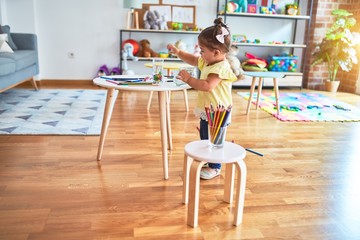 Beautiful toddler standing playing with chocolate colored balls on the table at kindergarten