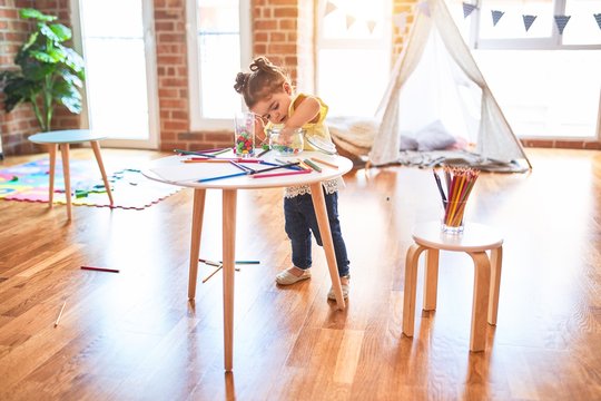 Beautiful toddler standing playing with chocolate colored balls on the table at kindergarten