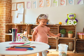 Beautiful blond toddler girl wearing princess crown standing at kindergarten