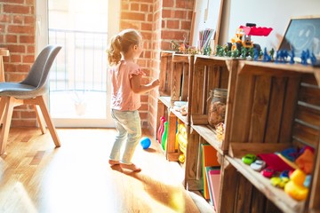 Beautiful blond toddler girl standing at kindergarten