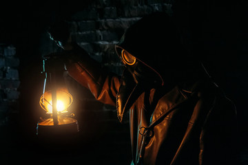 Terrible plague doctor with kerosene lamp. Masked maniac. Halloween and horror concept