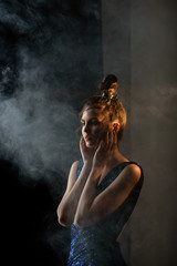 Young woman with smoke and movie light in a dark room