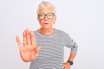 Senior grey-haired woman wearing striped navy t-shirt glasses over isolated white background doing stop sing with palm of the hand. Warning expression with negative and serious gesture on the face.