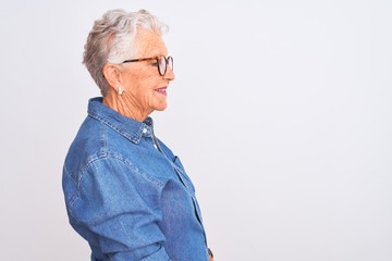 Senior grey-haired woman wearing denim shirt and glasses over isolated white background looking to...