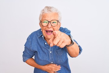 Senior grey-haired woman wearing denim shirt and glasses over isolated white background laughing at...
