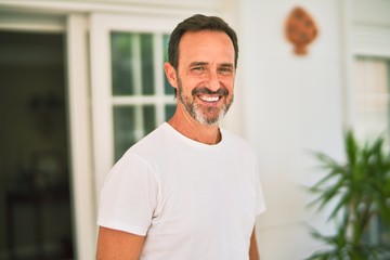 Fototapeta premium Middle age handsome man wearing casual t-shirt standing on terrace smiling
