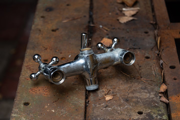 Old water mixing crane on a rusty metal workbench.