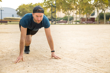 Athletic young man training for a race start in a park at the beginning of Autumn