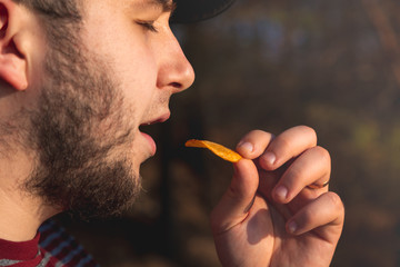 Bearder Man in forest eating chips. In park image outdoors with blurred background