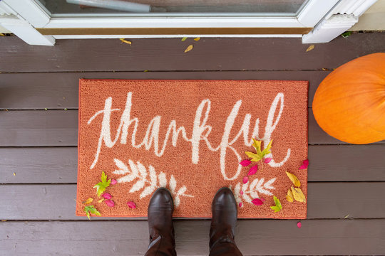 Welcome mat with the word "Thankful" on front doorstep