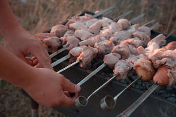 Man frying shish kebab on the grill. Hands closeup outdoors