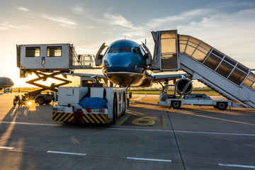 Airplane boarding , airplane airport boarding stairs, trucks and pushback vehicles with great sunset