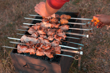 Man frying shish kebab on the grill. Hands closeup outdoors.