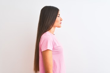 Young beautiful woman wearing pink casual t-shirt standing over isolated white background looking to side, relax profile pose with natural face with confident smile.