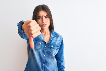 Young beautiful woman wearing casual denim shirt standing over isolated white background looking unhappy and angry showing rejection and negative with thumbs down gesture. Bad expression.