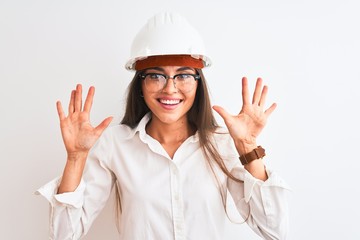 Young beautiful architect woman wearing helmet and glasses over isolated white background showing and pointing up with fingers number ten while smiling confident and happy.