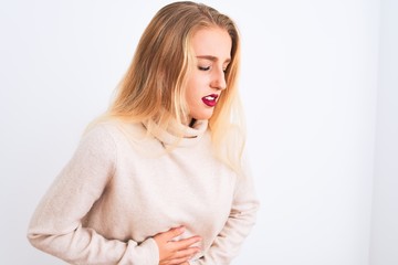 Young beautiful woman wearing turtleneck sweater standing over isolated white background with hand on stomach because indigestion, painful illness feeling unwell. Ache concept.