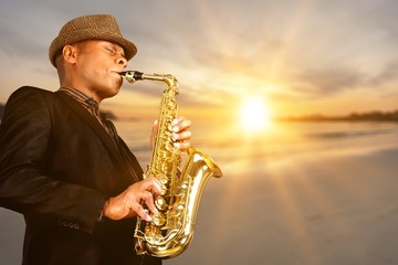 Close-up man playing on saxophone on blurred background - obrazy, fototapety, plakaty