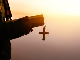 Human reading the holy bible and the cross necklace