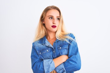 Young beautiful woman wearing casual denim shirt standing over isolated white background looking to the side with arms crossed convinced and confident