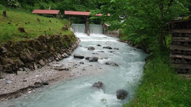 Water mill and flowing river in green forest near Partnach Gorge.