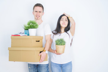 Fototapeta na wymiar Young beautiful couple holding cardboard boxes standing over isolated white background stressed with hand on head, shocked with shame and surprise face, angry and frustrated. Fear and upset 